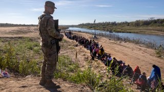 A Texas National Guard soldier watches over a group of more than 1,000 migrants